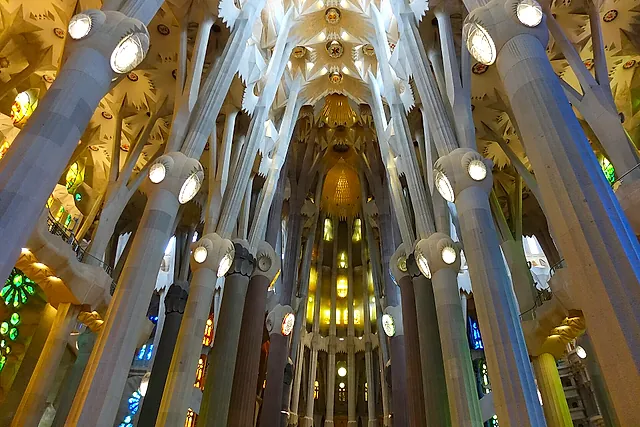 The nave seen towards the apse, with the tall branching columns and the warm light from the stained-glass windows